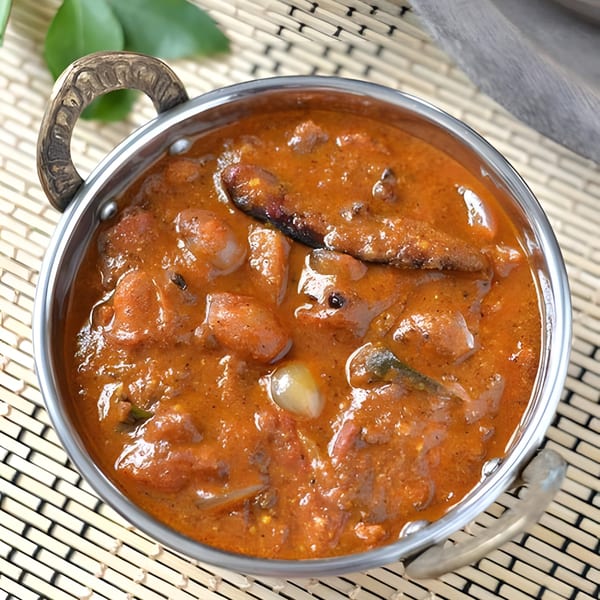 Madurai Sizzle Shack's Indian curry, a rich orange stew with meat and vegetables in a metal bowl.