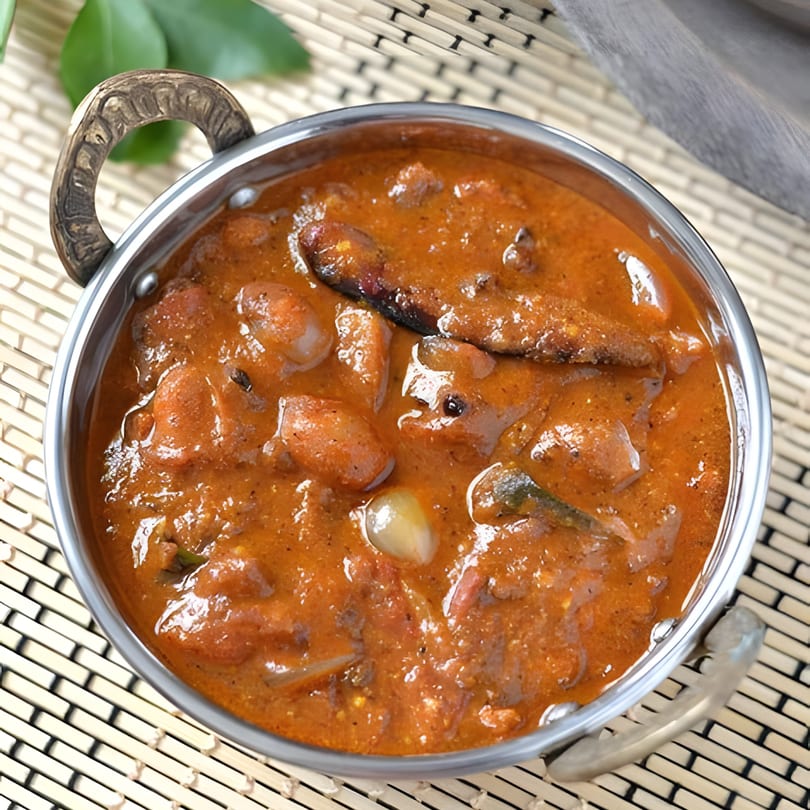 Madurai Sizzle Shack's Indian curry, a rich orange stew with meat and vegetables in a metal bowl.