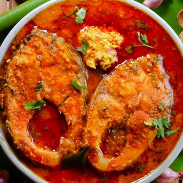 Two fish steaks in a rich red curry sauce, garnished with cilantro and a dollop of spice paste.